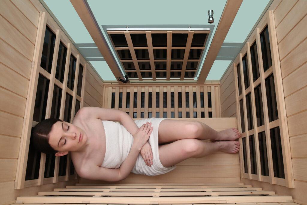 Inside view from above of 2 person infrared sauna with 360° placement of heater panels and occupant sitting with legs up