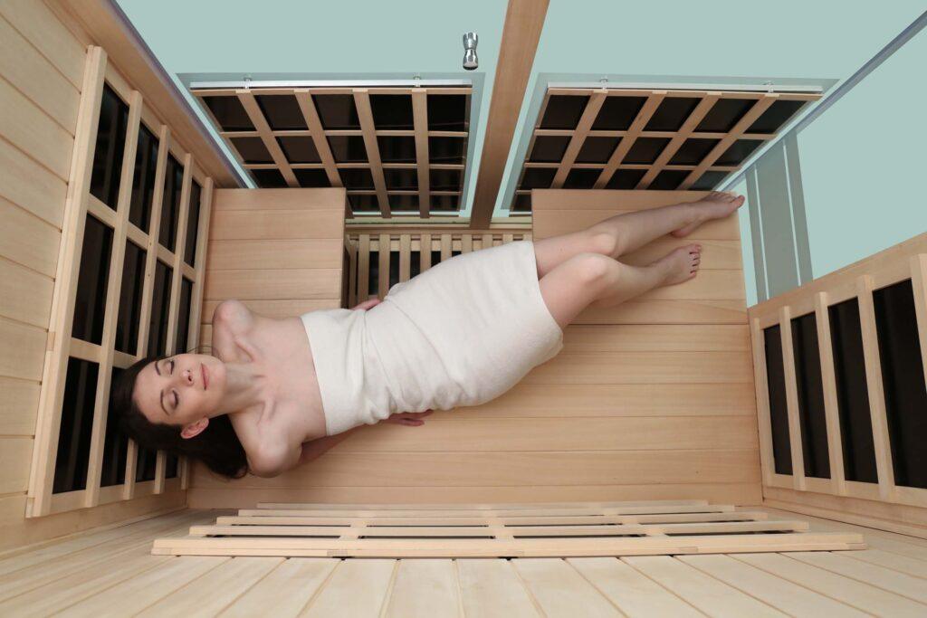 Inside top view of 3 person infrared sauna showing occupant lady laying horizontal